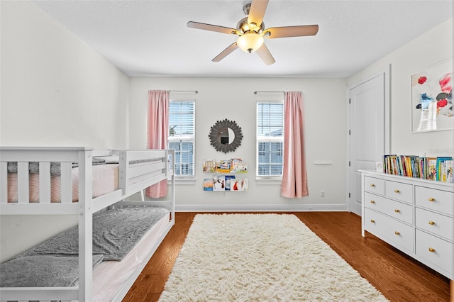 bedroom featuring a textured ceiling, wood finished floors, baseboards, and ceiling fan