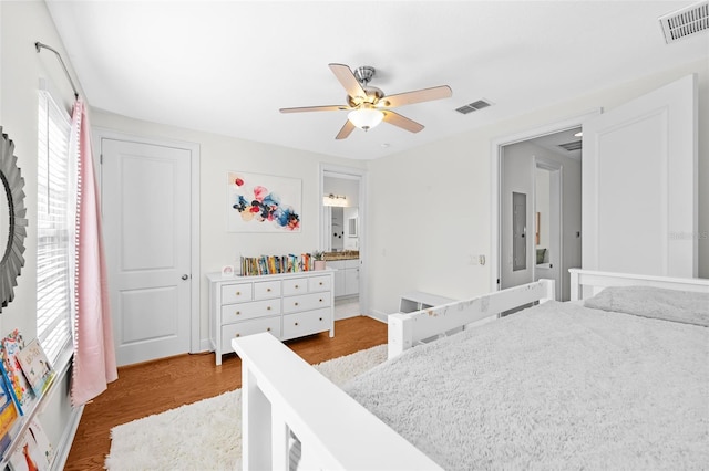 bedroom with wood finished floors, visible vents, ensuite bathroom, and ceiling fan