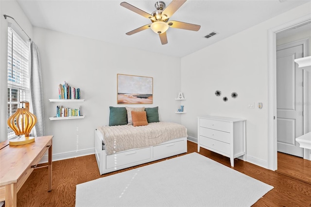 bedroom featuring visible vents, ceiling fan, baseboards, and wood finished floors