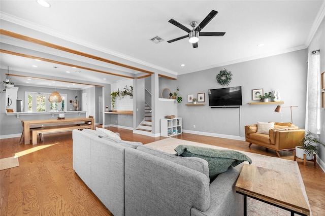 living area with visible vents, crown molding, baseboards, ceiling fan, and stairway