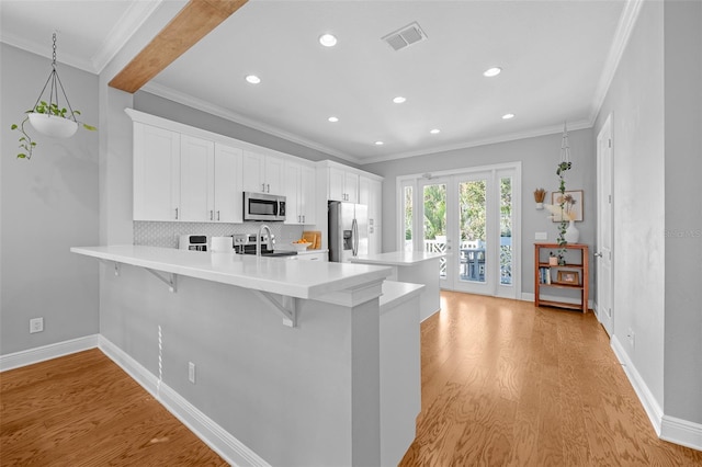 kitchen featuring backsplash, light countertops, light wood-type flooring, appliances with stainless steel finishes, and a kitchen breakfast bar