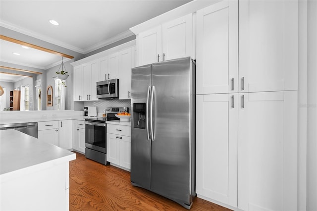 kitchen with white cabinetry, light countertops, crown molding, and stainless steel appliances