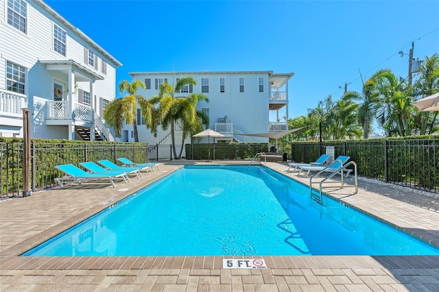 community pool with a patio and fence