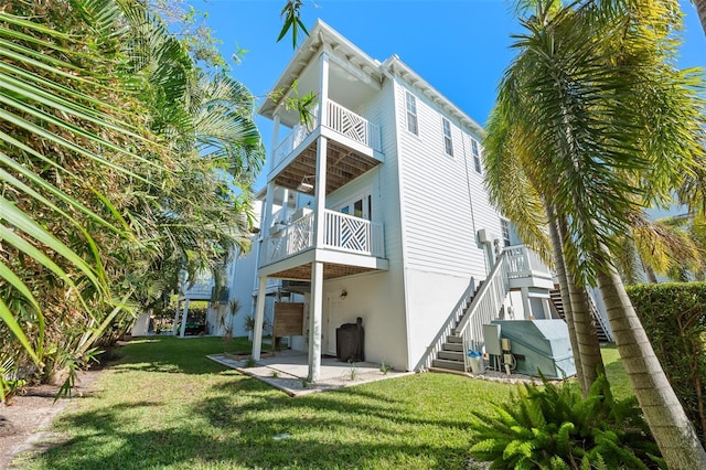 rear view of house with a patio area, a lawn, stairs, and a balcony