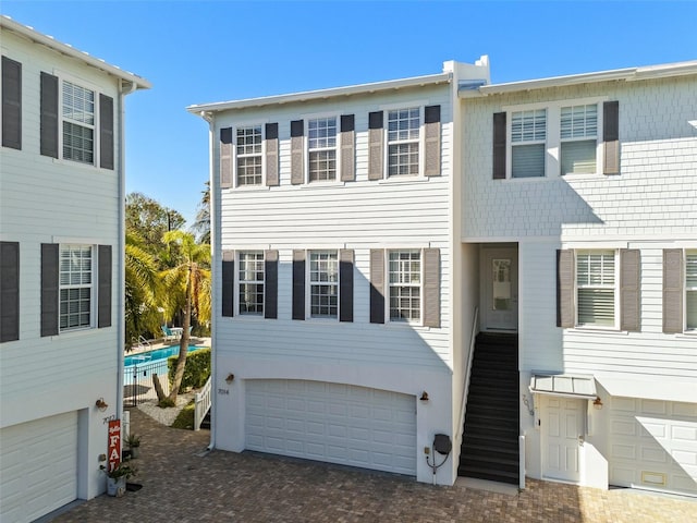 back of property with an attached garage and stairs