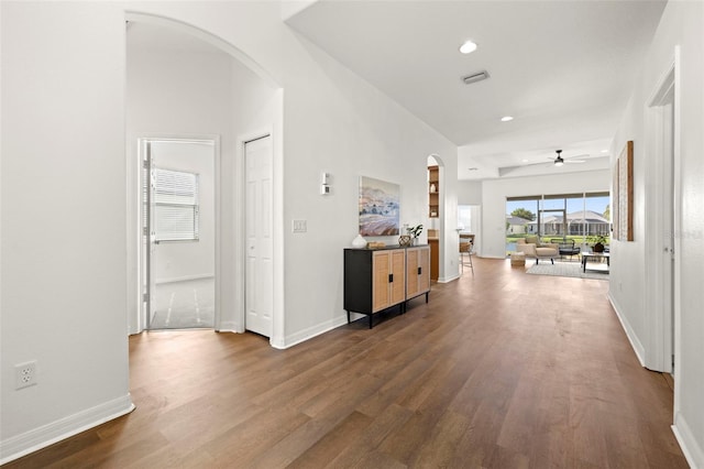 hall featuring visible vents, recessed lighting, arched walkways, baseboards, and dark wood-style flooring