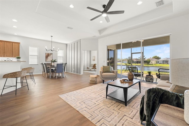 living area featuring light wood-type flooring, visible vents, recessed lighting, baseboards, and a raised ceiling