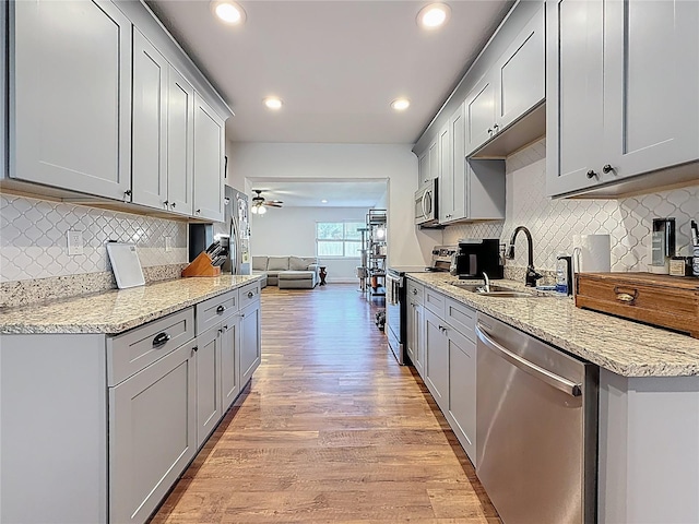 kitchen with light wood-style flooring, gray cabinets, appliances with stainless steel finishes, and a sink