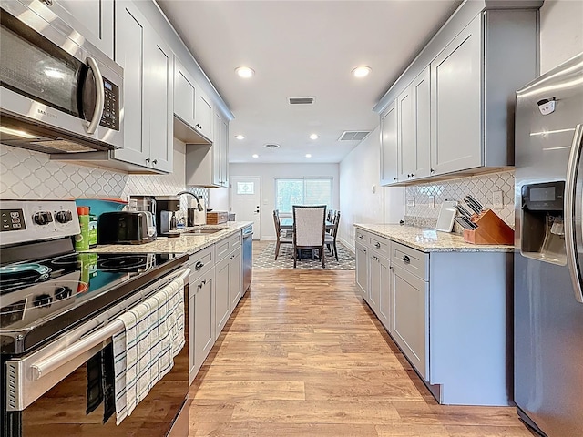 kitchen with a sink, visible vents, light wood finished floors, and stainless steel appliances