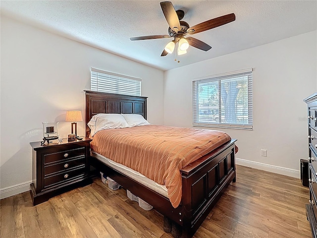 bedroom featuring baseboards, a textured ceiling, wood finished floors, and a ceiling fan