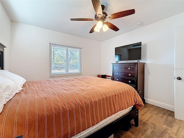 bedroom with light wood-style flooring, baseboards, and ceiling fan