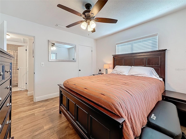 bedroom with light wood finished floors, visible vents, a textured ceiling, and ceiling fan