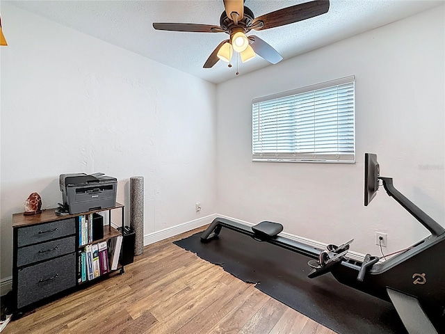 workout room with a textured ceiling, wood finished floors, baseboards, and ceiling fan