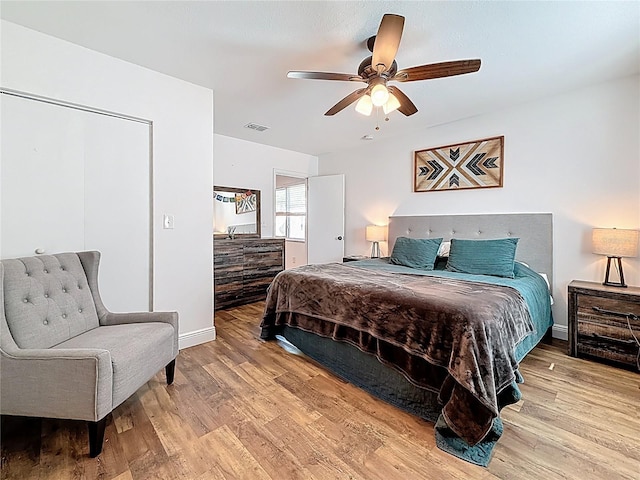 bedroom featuring a ceiling fan, wood finished floors, visible vents, and baseboards