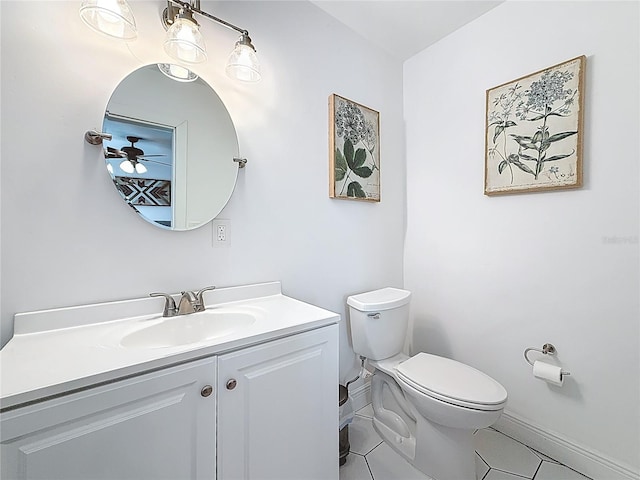 half bathroom featuring vanity, baseboards, ceiling fan, tile patterned flooring, and toilet