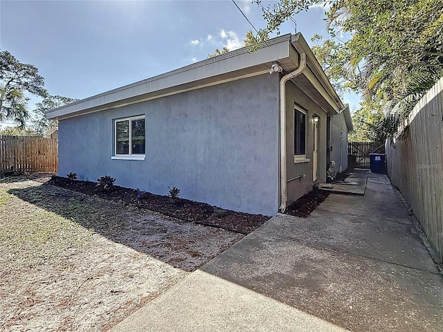 view of side of home featuring stucco siding, a patio, and a fenced backyard