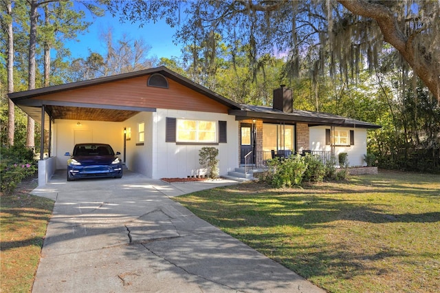 ranch-style house with a carport, a chimney, concrete driveway, and a front lawn