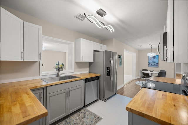 kitchen featuring a sink, white cabinets, appliances with stainless steel finishes, and butcher block counters