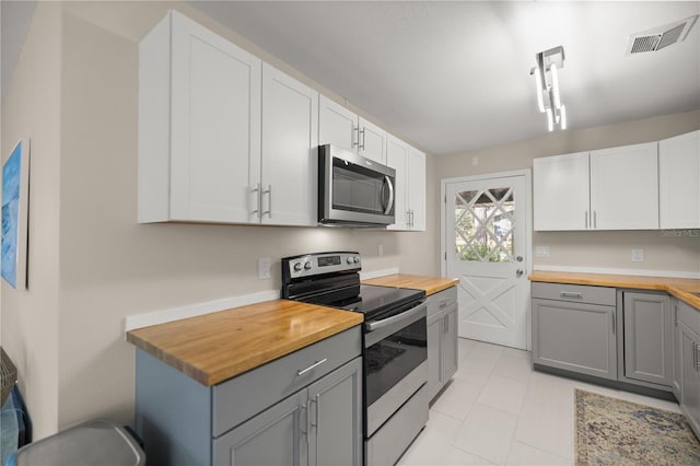 kitchen featuring visible vents, appliances with stainless steel finishes, gray cabinets, and butcher block counters