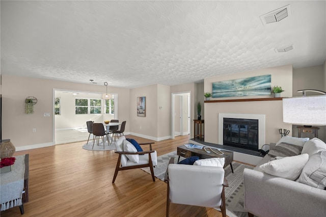 living room featuring visible vents, light wood-style floors, and a textured ceiling