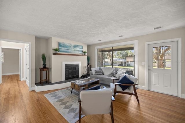 living room featuring a wealth of natural light, visible vents, and light wood-type flooring