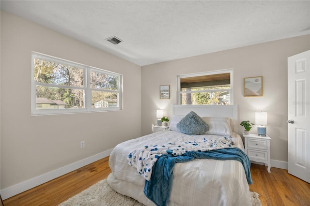 bedroom featuring visible vents, baseboards, and light wood-style floors