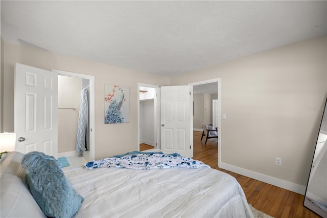 bedroom with a walk in closet, baseboards, and wood finished floors