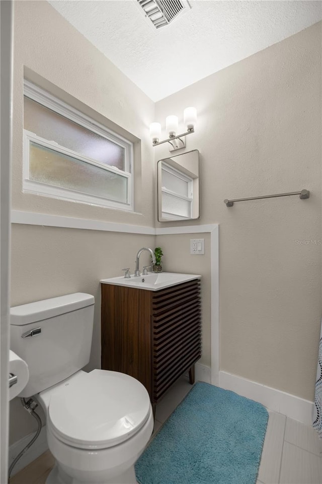 bathroom featuring tile patterned flooring, visible vents, baseboards, toilet, and vanity