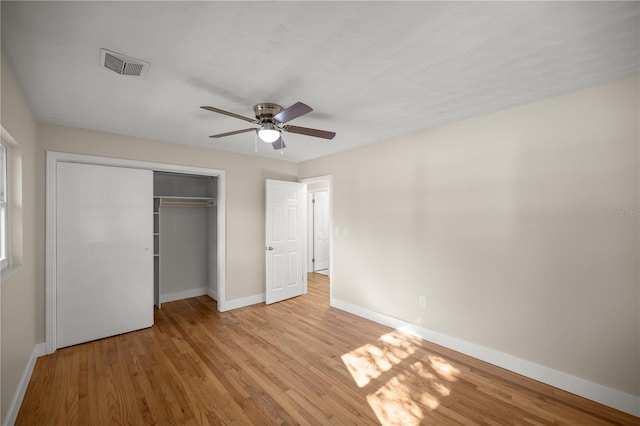 unfurnished bedroom with wood finished floors, visible vents, baseboards, ceiling fan, and a closet