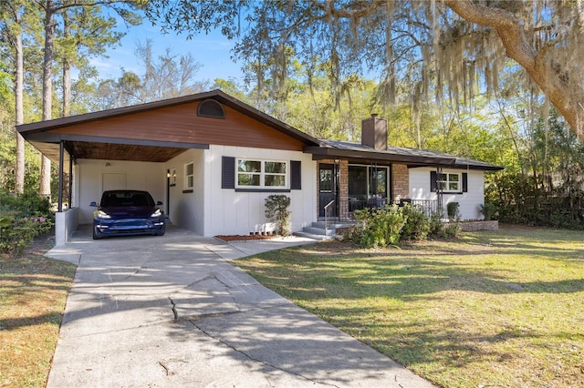 ranch-style house featuring driveway, board and batten siding, a front yard, an attached carport, and a chimney