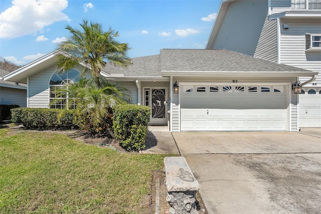 view of front facade featuring a front yard, concrete driveway, an attached garage, and a shingled roof