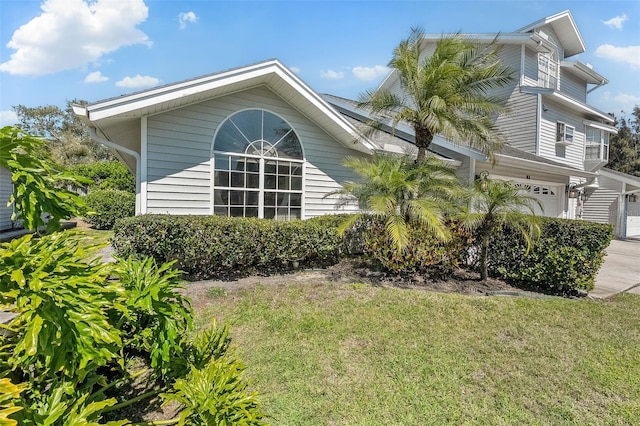 view of side of property with a lawn, a garage, and driveway