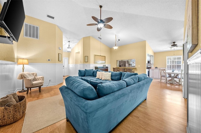 living area with visible vents, a wainscoted wall, a ceiling fan, and light wood-style flooring