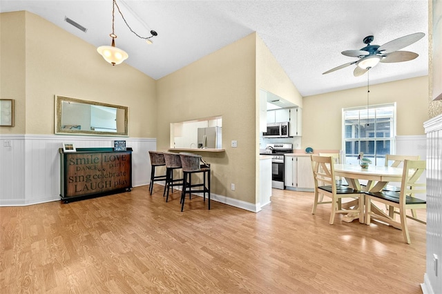 interior space featuring light wood-type flooring, visible vents, a ceiling fan, and vaulted ceiling