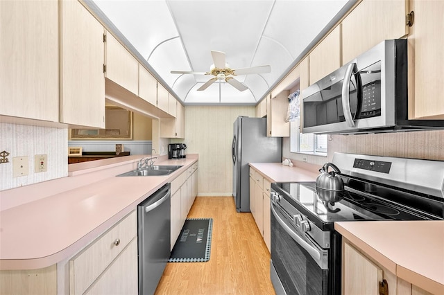 kitchen with a sink, ceiling fan, light countertops, stainless steel appliances, and light wood-style floors