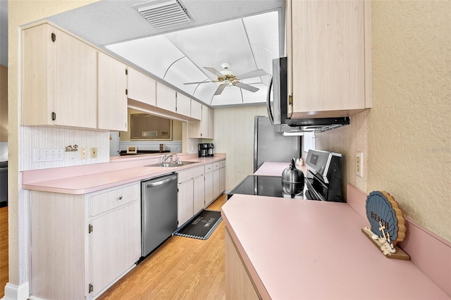 kitchen featuring visible vents, light wood-style flooring, a sink, appliances with stainless steel finishes, and light countertops