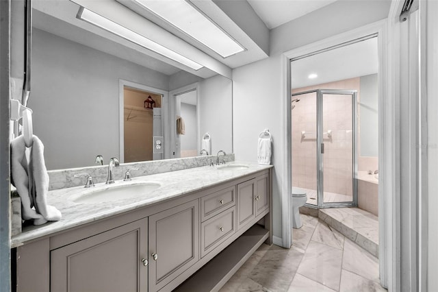 bathroom with a shower stall, double vanity, and a sink