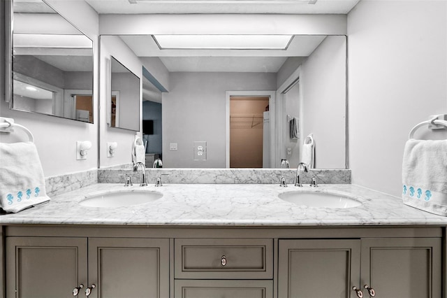 bathroom featuring a walk in closet, double vanity, and a sink