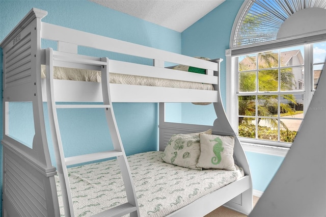 bedroom with lofted ceiling, a textured wall, and a textured ceiling