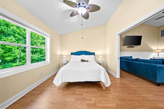 bedroom featuring ceiling fan, visible vents, baseboards, and wood finished floors