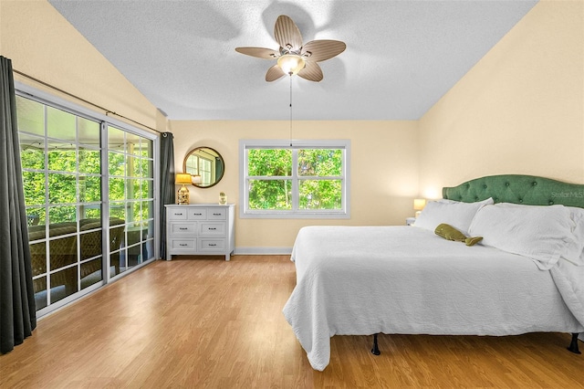 bedroom with a ceiling fan, vaulted ceiling, wood finished floors, and a textured ceiling