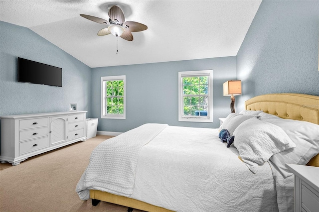 bedroom featuring light colored carpet, a ceiling fan, lofted ceiling, and a textured wall