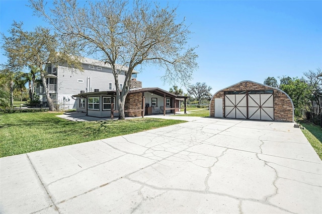 view of front of home with an outbuilding, a front lawn, stone siding, a detached garage, and a chimney