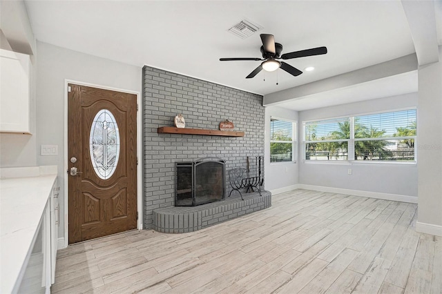 unfurnished living room with a ceiling fan, visible vents, baseboards, a fireplace, and light wood-type flooring