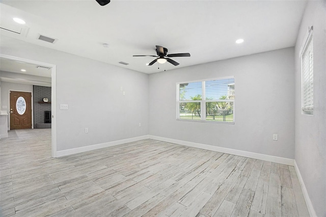 unfurnished room featuring visible vents, baseboards, light wood-style flooring, and a fireplace