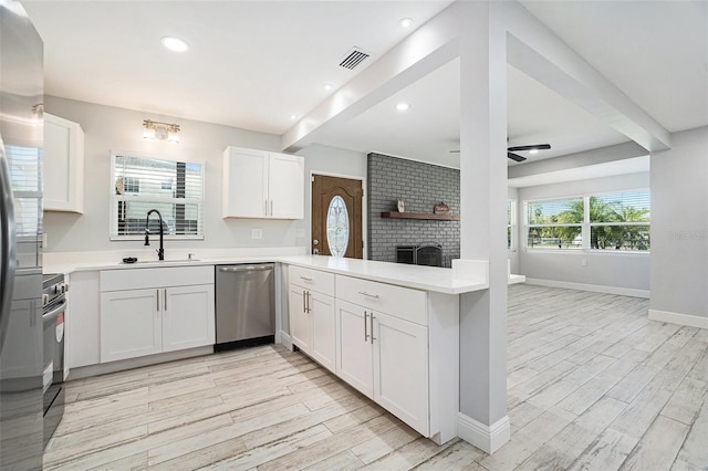 kitchen featuring beamed ceiling, open floor plan, a peninsula, stainless steel dishwasher, and a sink