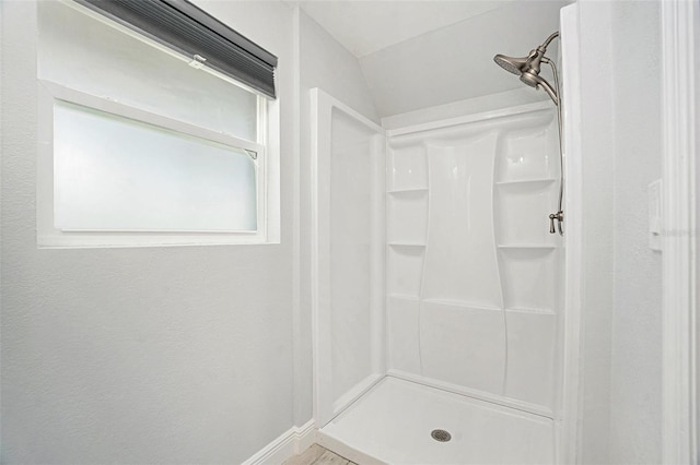 full bath with a shower stall, baseboards, and vaulted ceiling