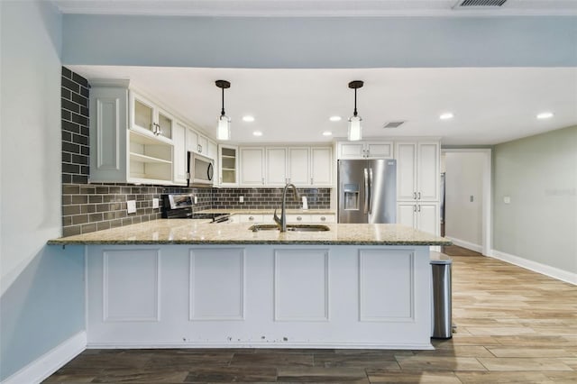 kitchen featuring light stone counters, backsplash, appliances with stainless steel finishes, and a sink