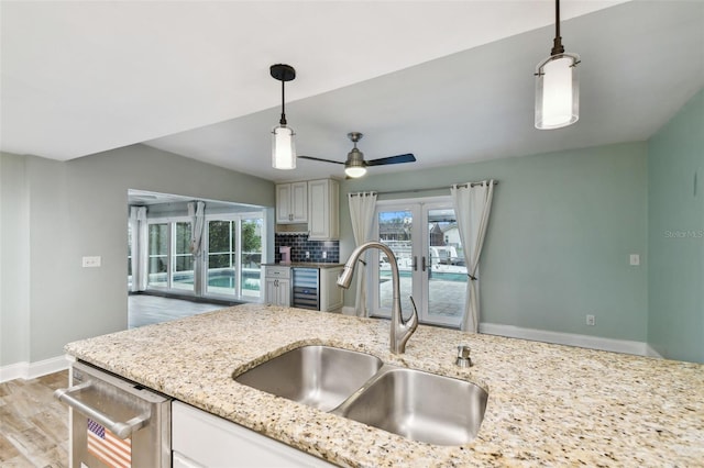 kitchen with pendant lighting, a sink, french doors, light stone countertops, and dishwasher