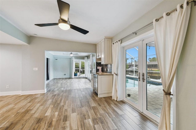 interior space featuring backsplash, french doors, baseboards, and light wood finished floors